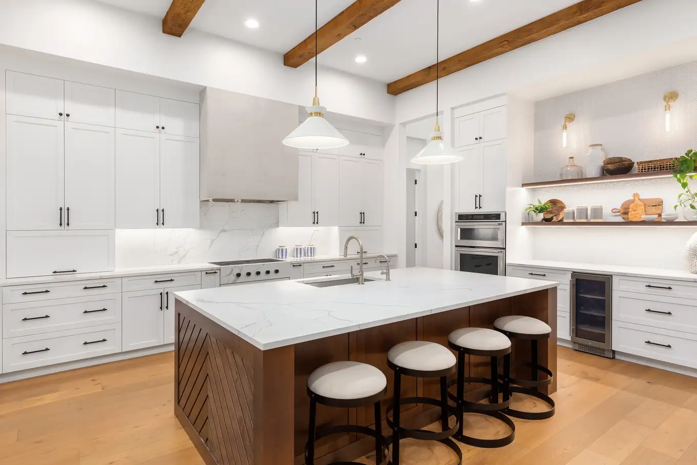 Modern kitchen remodel with white cabinets, wood beams, and marble island